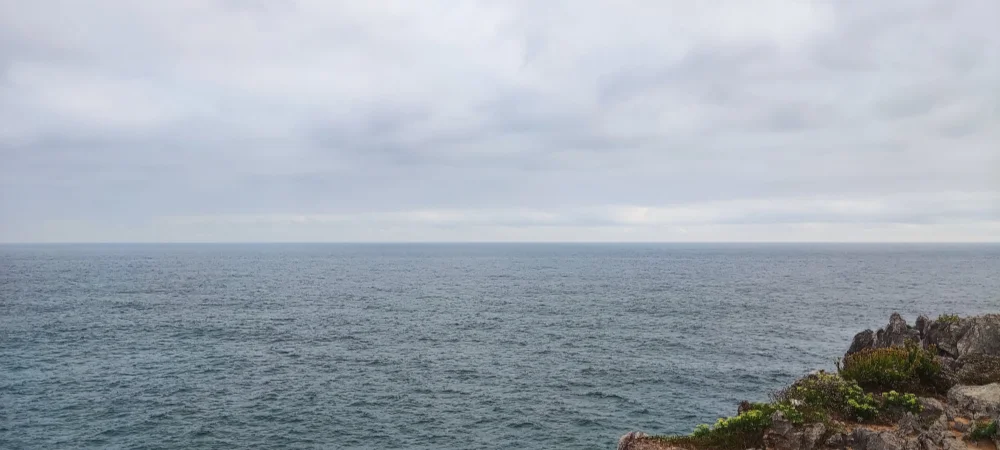 Fotografía con vistas a la costa del norte de España,
          centrada en el horizonte donde se juntan el mar y el cielo.